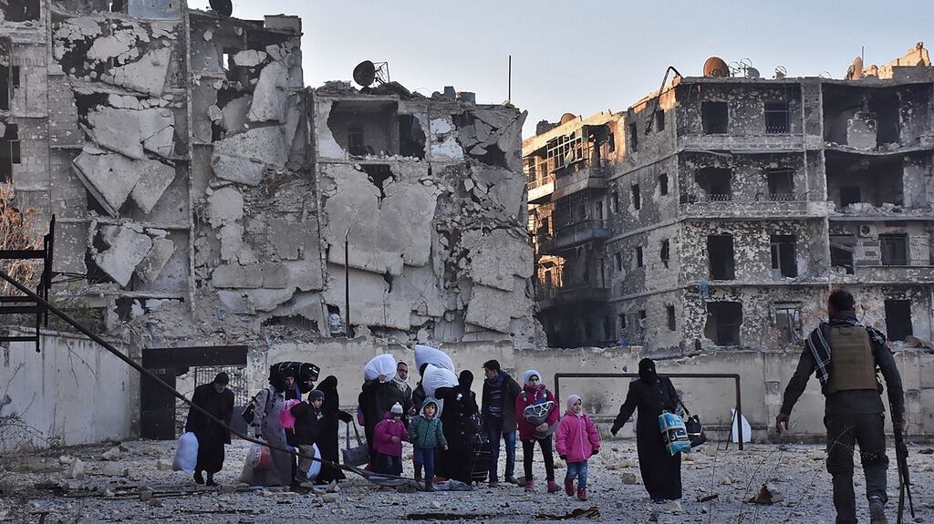 Syrian residents flee violence in the eastern rebel-held parts of Aleppo through the Bab al-Hadid district after it was seized by government forces. Photograph: George Ourfalian/AFP/Getty