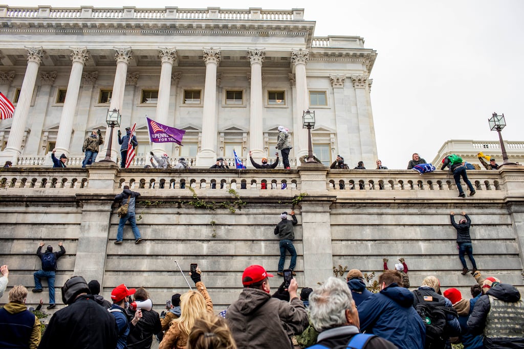 Supporters of then US president Donald Trump scale a wall on the Senate side of the Capitol before storming the building in an attempt to disrupt the certification of the Electoral College results on January 6th, 2021. Photograph: Jason Andrew/The New York Times
