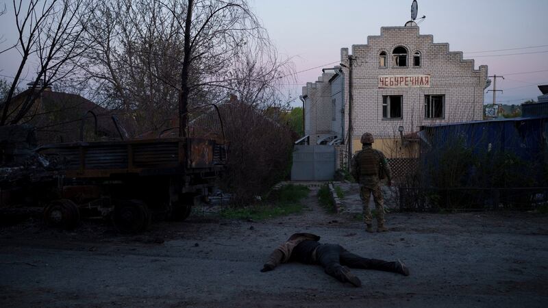 A Ukrainian serviceman stands next to the body of a suspected Russian soldier, in the village of Vilkhivka, recently retaken by Ukraininan forces near Kharkiv on Monday. Photograph: Felipe Dana/AP