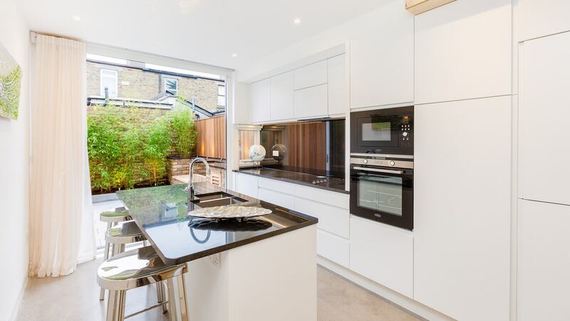 The kitchen – white units topped with black granite – features an island.