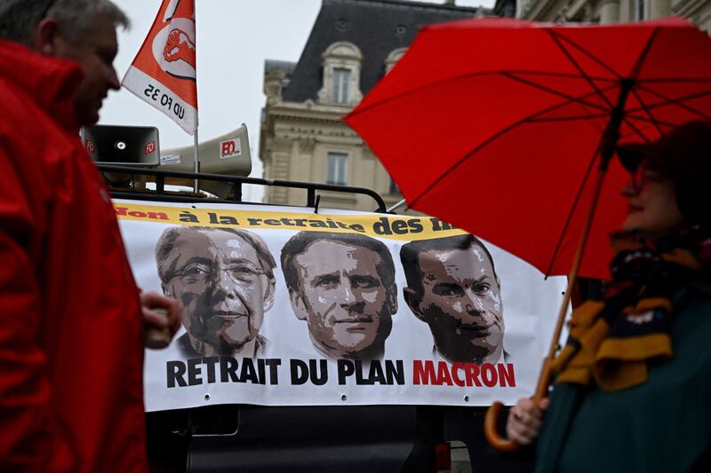 Protesters in Rennes stand in front of a banner bearing portraits of prime minister Elisabeth Borne and President Emmanuel Macron and Labour minister Olivier Dussopt. It states: 'No pension for the dead people'. Photograph: Damien Meyer