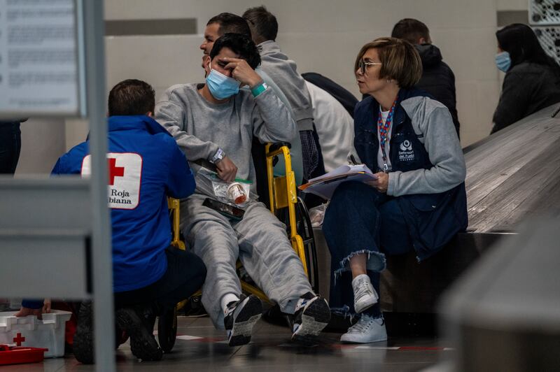 A Colombian Red Cross worker and a worker with the ombudsman’s office of Colombia  speak at El Dorado airport in Bogotá on Tuesday with a Colombian man deported from the US. Photograph: Federico Rios/New York Times