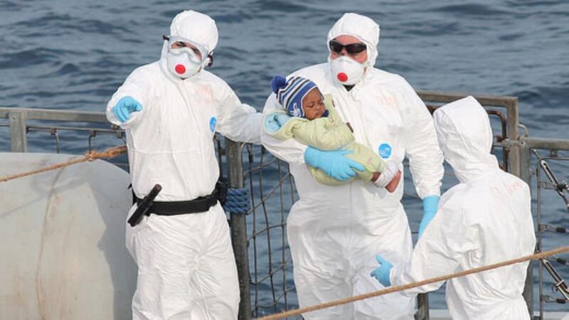 Rescuers hold a child rescued from a small rubber craft in the Mediterranean on Saturday. Photograph: Irish Defence Forces