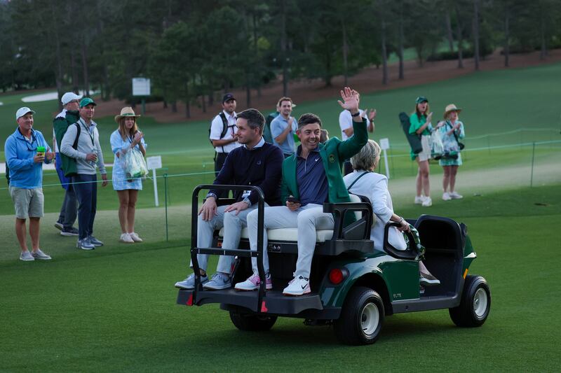 Rory McIlroy waves from a buggy with manager Sean O'Flaherty after the Green Jacket ceremony. Photograph: Andrew Redington/Getty