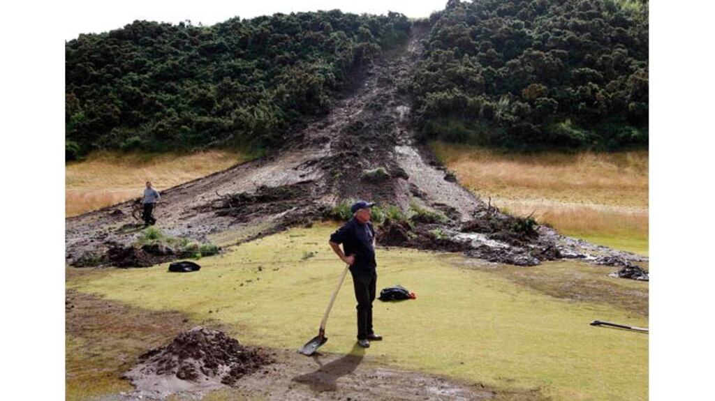 A green keeper stands in front of a landslide on the twelfth fairway on the third day of the Scottish Open golf tournament at Castle Stuart, near Inverness. Play was suspended after heavy overnight rainfall resulted in landslides and floods. - (Photograph: David Moir/Reuters)
