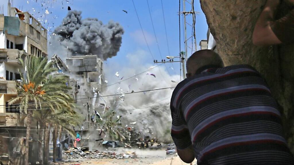 Palestinians take cover as smoke rises after Israeli warplanes targeted a house in the Al-Shatea refugee camp in the west of Gaza City yesterday. Photograph: EPA/Mohammed Saber