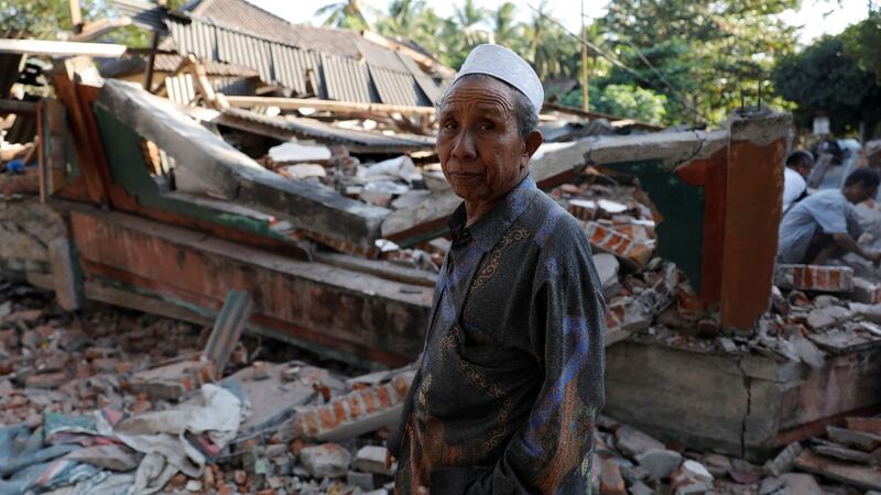 A villager walks through a collapsed house after an earthquake hit Lombok Island in Indonesia. Photograph: Beawiharta/Reuters