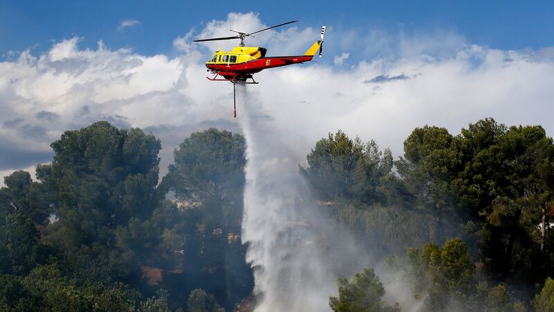 A firefighting helicopter drops water over a forest fire in Carros near Nice. Photograph: Sebastien Nogier/EPA
