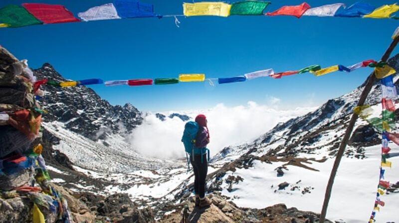A woman stands among prayer flags marking the top of the Laurebina La which is the pass between the Langtang region and Helmabu in Nepal