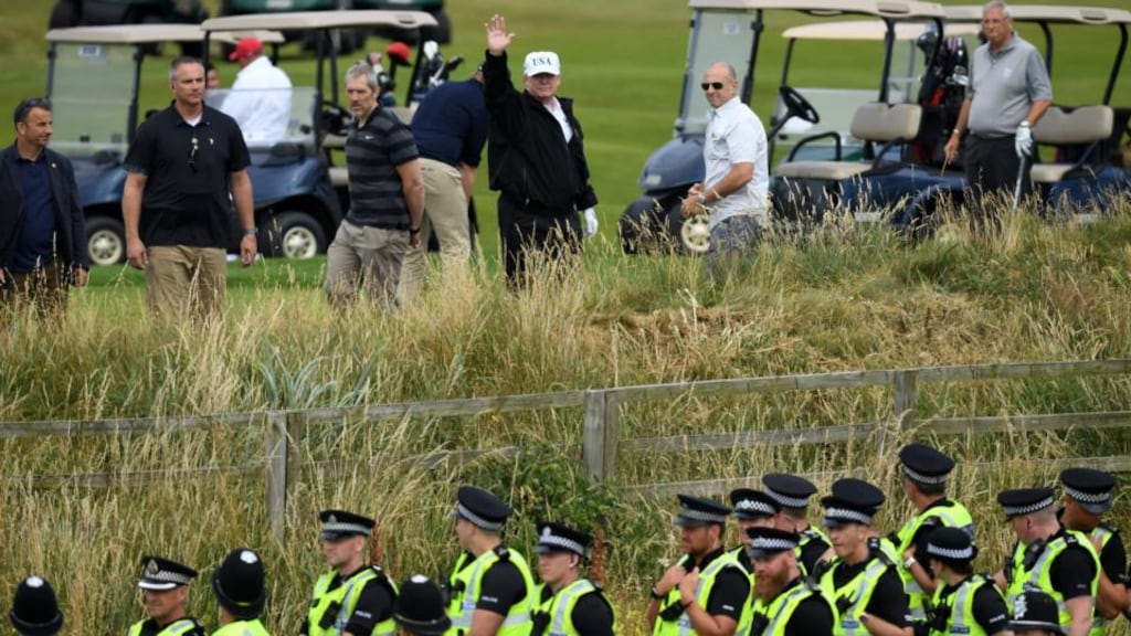 Scottish police secure the area as US president Donald Trump waves while playing golf at Trump Turnberry golf resort during his first official visit to the UK. Photograph: Leon Neal/Getty Images