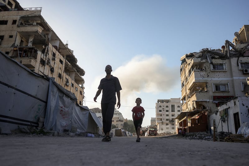 A Palestinian child and a man walk past tents for displaced people set up amid the ruins of buildings in Gaza City. The Israeli military has declared Gaza City 'a dangerous combat zone'. Photograph: Bashar Taleb/AFP via Getty Images