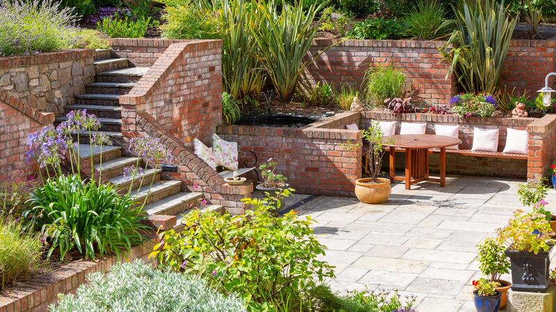 Patio in red brick and Indian sandstone with several seating areas.