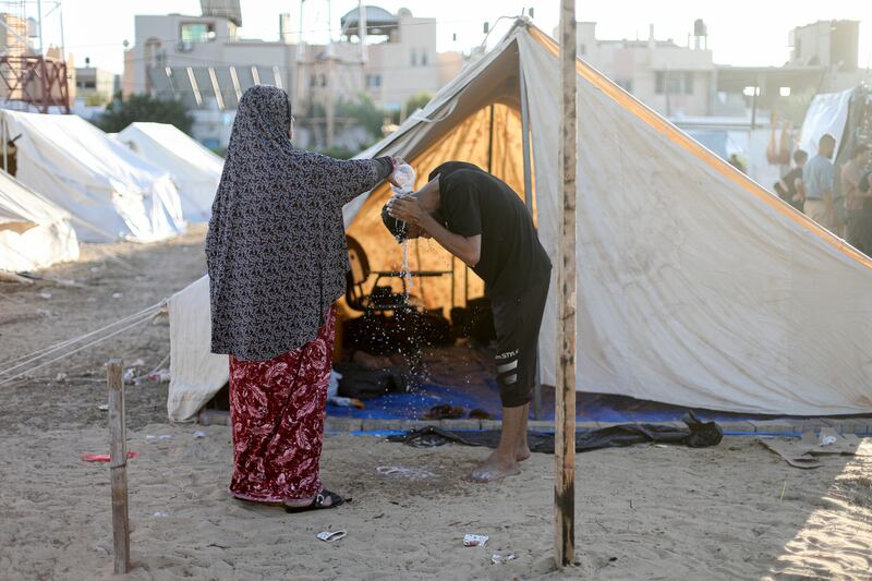 A woman pours water on her son in a shelter set up in the Khan Younis training centre in the southern Gaza Strip. Photograph: Yousef Masoud/New York Times