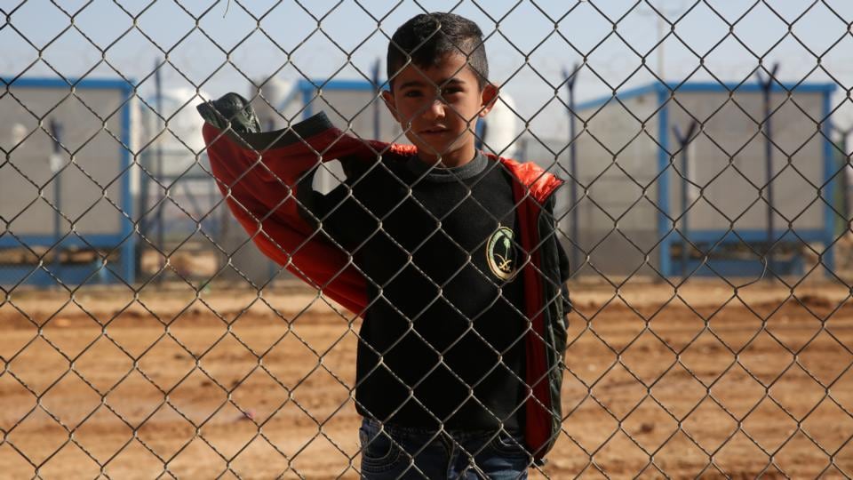 A boy stands behind a fence at Zaatari camp in Jordan, currently home to 80,000 Syrian refugees. Photograph: Sally Hayden
