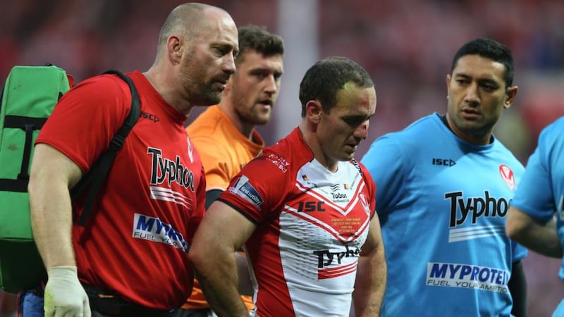 Lance Hohaia (centre) of St Helens is helped off the field by medics after being punched by Ben Flower of Wigan. Photograph: Michael Steele/Getty Images