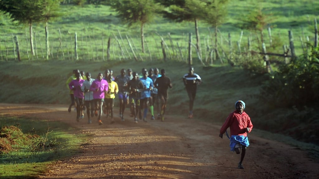 A young girl on her way to school runs ahead of a group of elite runners out for a morning workout at Kaptagat in Eldoret town. Photograph: Tony Karumba/AFP/Getty