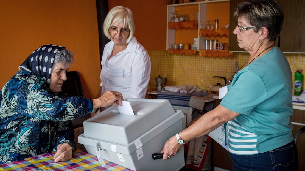 A woman votes on mandatory refugee acceptance as others hold up a mobile ballot box in Kelebia, 191km south of Budapest. Photograph: Sandor Ujvari/EPA
