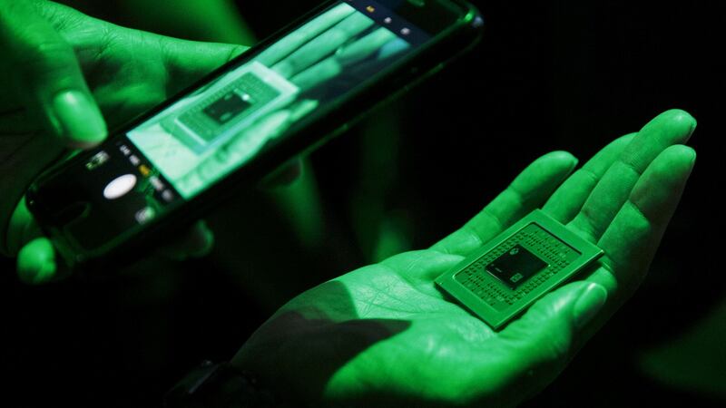 An attendee takes a photograph while holding a processor for the Xbox One X console during a Microsoft event ahead of the E3 Electronic Entertainment Expo in Los Angeles. Photograph: Patrick T Fallon/Bloomberg
