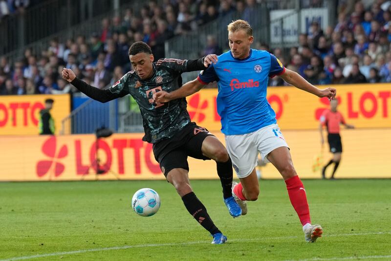 Jamal Musiala (L) in action against Timo Becker (R) during the German Bundesliga soccer match between Holstein Kiel and FC Bayern Munich, in Kiel, Germany, 14 September 2024.