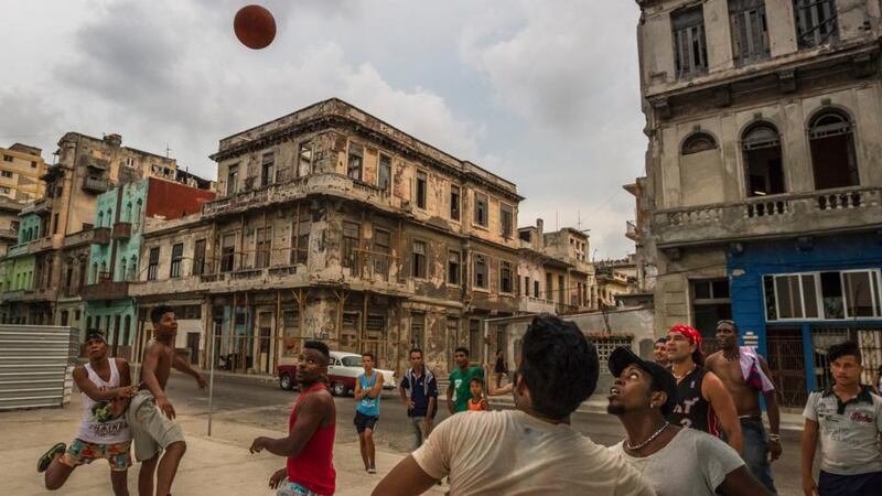 Young men play basketball on an improvised court wedged between a construction site and the shells of once grand colonial homes in Havana. Photograph: Meridith Kohut/The New York Times