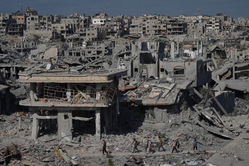 Palestinians walk past destroyed buildings in Khan Younis, in the southern Gaza Strip. Photograph: Jehad Alshrafi/AP