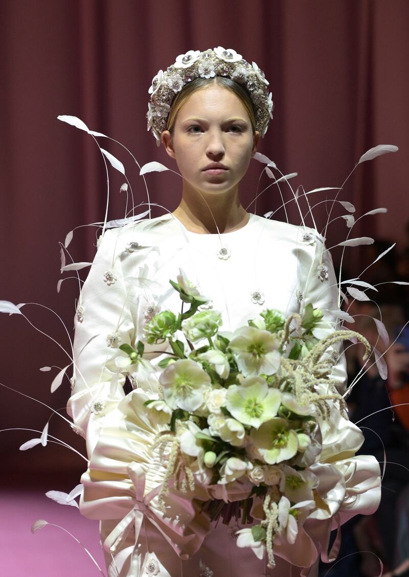 Lila Moss, Kate Moss’s 19-year-old daughter, looking wistful wearing a Richard Quinn look comprising a short white dress with flying feathers, a silver crown and holding a white bouquet. Photograph: Gareth Cattermole/Getty Image