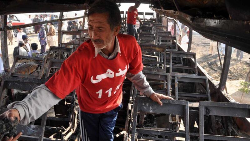 Pakistani rescue workers inspect the wreckage of a bus after it collided with an oil tanker and burst into flames, near Karachi, Pakistan. Photograph: EPA