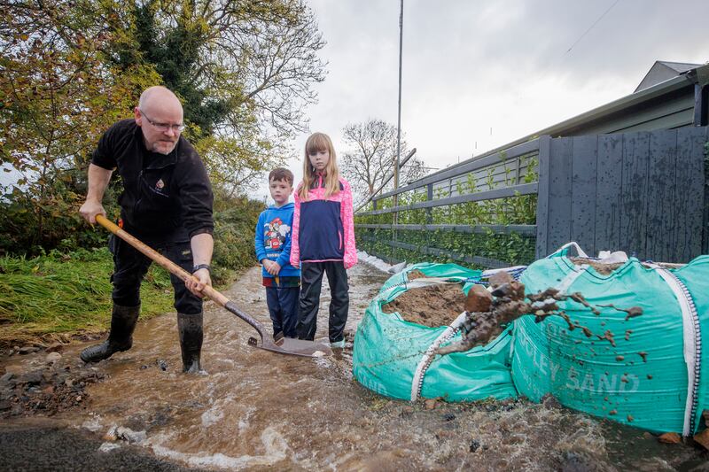 Damien McShane with his son Ryan and daughter Maevh clear a path to their house on the outskirts of Carlingford after heavy rainfall. Photograph: Liam McBurney/PA Wire