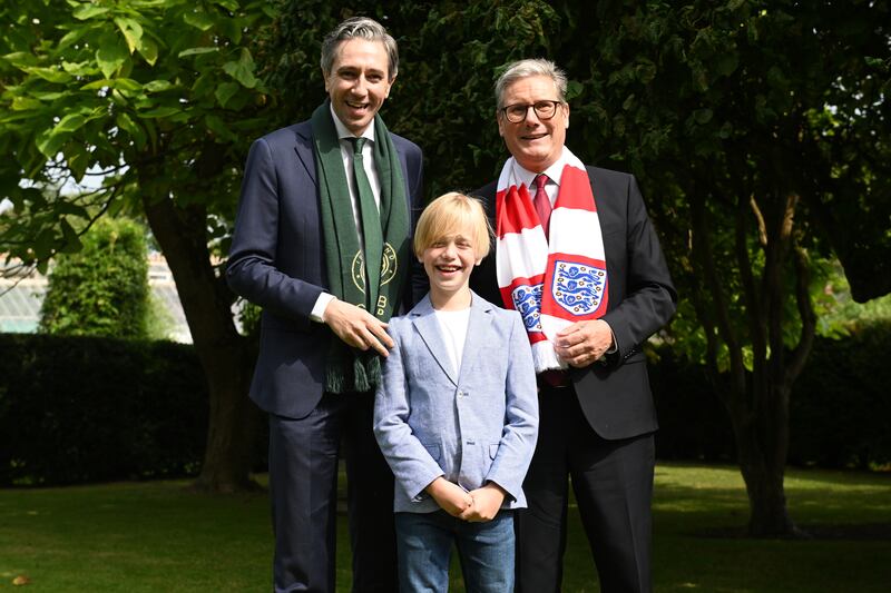 Taoiseach Simon Harris and prime minister Keir Starmer, wearing Irish and England team scarfs pose for a photograph with Freddie Munnelly (9), as they meet for talks at Farmleigh House in Dublin. Photograph: Charles McQuillan/PA Wire