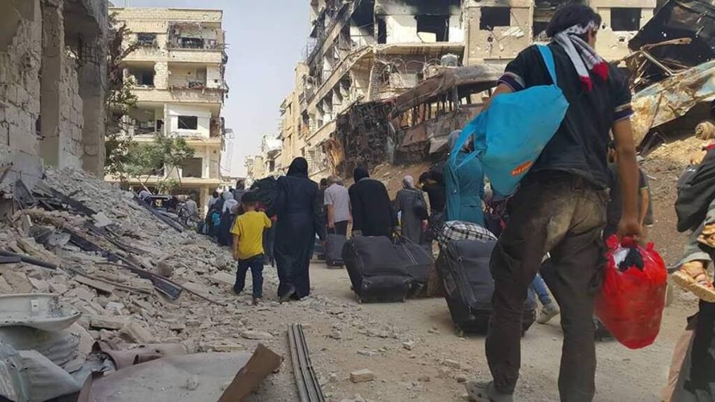 People carry their belongings before being evacuated from the besieged Damascus suburb of Daraya. Photograph: Sana/handout via Reuters