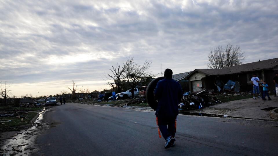A man carries a tyre, which he found several blocks away, down the street back to his tornado-damaged house in Moore, Oklahoma. Photograph: Rick Wilking/Reuters