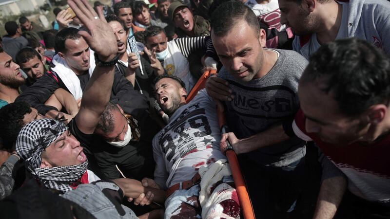 Palestinian protesters carry a wounded man from during a protest at the Gaza Strip’s border with Israel. Photograph:  Khalil Hamra/AP