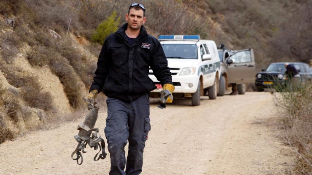 An Israeli police explosive expert carries the remains of a rocket after it landed near the northern town of Kiryat Shmona today. Photograph: Reuters