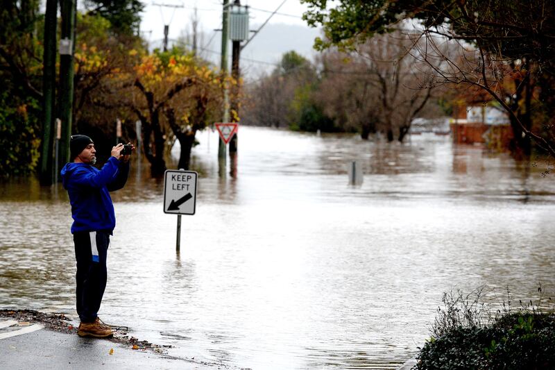 A man takes pictures of the flooded streets in the Camden suburb of Sydney on Sunday. Photograph: Muhammad Farooq/AFP via Getty Images