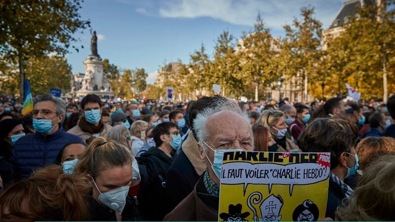 A protester holds a copy of the satirical newspaper Charlie Hebdo during an anti-terrorism vigil on Sunday at Place de La Republique in Paris for the murdered schoolteacher Samuel Paty. Photograph: Kiran Ridley/Getty Images