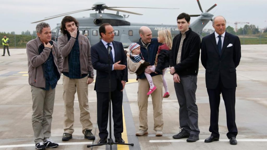 French president Francois Hollande (C) speaks with former French hostages and journalists, from L-R, Didier Francois, Edouard Elias , Nicolas Henin, who holds his children, Pierre Torres and France’s roreign minister Laurent Fabius, moments after their arrival by helicopter from Evreux to the military airbase in Villacoulbay, near Paris today. Photograph: Reuters