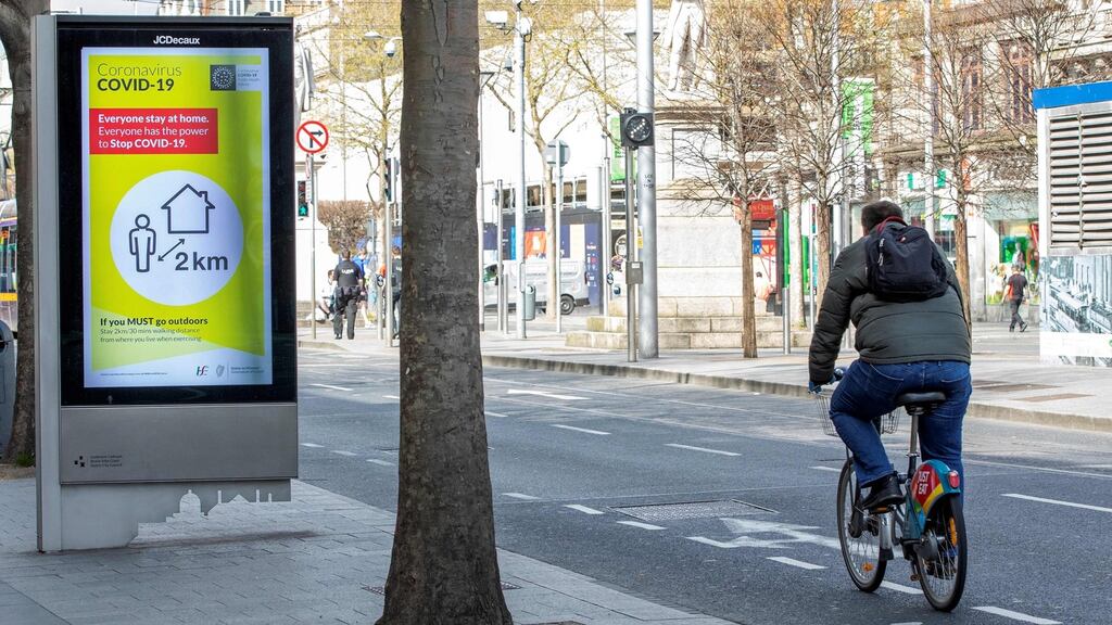A cyclist passes a poster alerting the public that if they must leave their home, they must stay within a 2km radius of their home, on Dublin’s O’Connell Street earlier this month. Photograph: Paul Faith/AFP via Getty