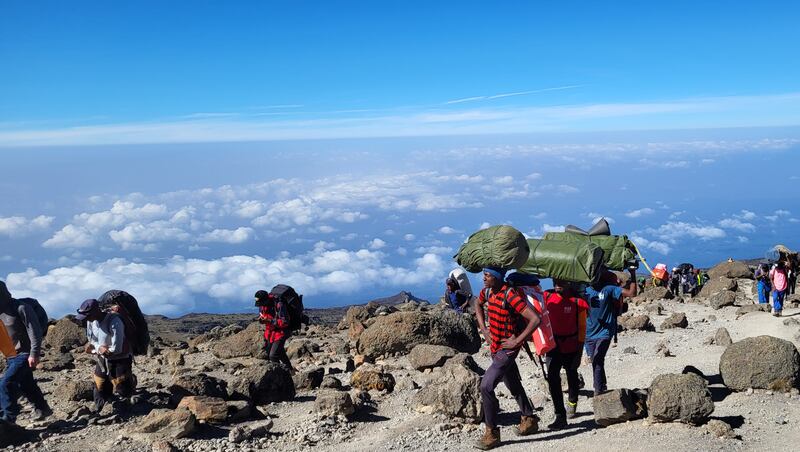 Tanzanian porters carrying luggage up Kilimanjaro. Photograph: Shauna Bowers