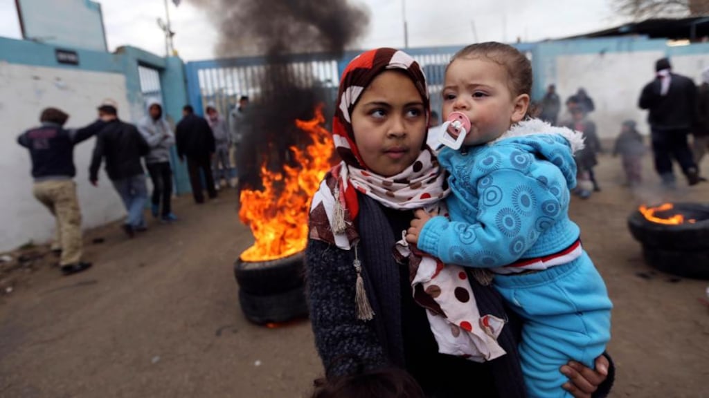 A Palestinian girl carries her sister during a protest in the southern Gaza Strip calling for reconstruction of houses. Some 150,000 Gazans remain homeless. Photograph: Ibraheem Abu Mustafa/Reuters