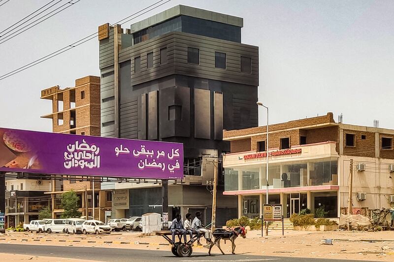 Men ride in a donkey-drawn cart near the burnt-down headquarters of Sudan's Central Bureau of Statistics in the south of Khartoum. Photograph: AFP