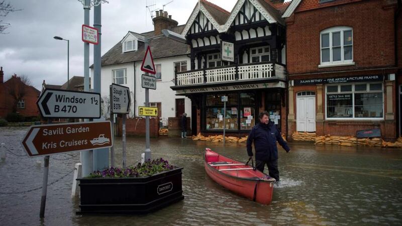 A man pushes his boat through the flooded central square in the village of Datchet in Berkshire, southern England. Photograph: Kieran Doherty/Reuters