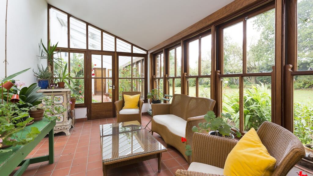 Doors from the kitchen open into a long, narrow conservatory with a brick floor, and through more doors into the greenhouse, where vines and tomatoes grow