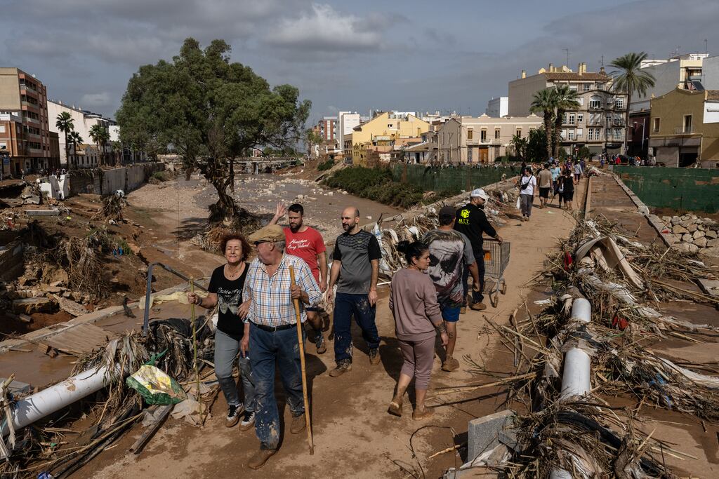 People cross a bridge through piles of debris after floods hit parts of the country in the Paiporta municipality of Valencia, Spain on Thursday. Photograph: David Ramos/Getty Images