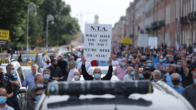 A man holding up a protest sign (centre), amongst taxi drivers, taking part in a protest in Merrion Square, Dublin, calling for greater support for the sector. Photograph: PA
