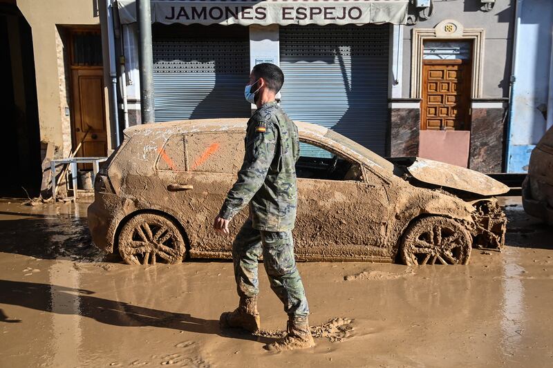 A soldier walks past a flood-damaged car in Massanassa, in the region of Valencia, eastern Spain. Photograph: JOSE JORDAN/AFP via Getty Images