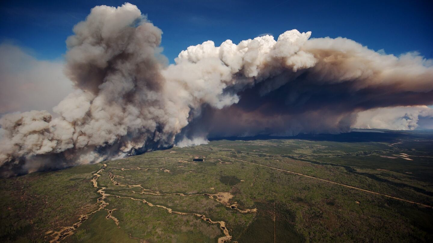 Huge plumes of smoke rise into the air as an out of control wildfire burns near Fort McMurray, Alberta, Canada, on Friday, May 6, 2016. The wildfires ravaging Canada's oil hub in northern Alberta have rapidly spread to an area bigger than New York city, prompting the air lift of more than 8,000 evacuees as firefighters seek to salvage critical infrastructure. Photographer: Darryl Dyck/Bloomberg