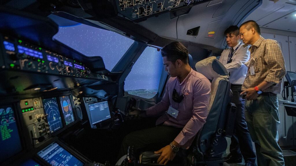 Thai Airways pilot Akarapol Apanant demonstrates the controls as visitors to the airline’s flight simulator look on. Photograph: Sakchai Lalit/AP