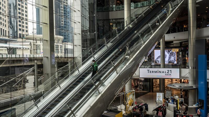 A food delivery worker rides down an escalator at a normally bustling shopping mall in Bangkok. Photograph: Adam Dean/The New York Times