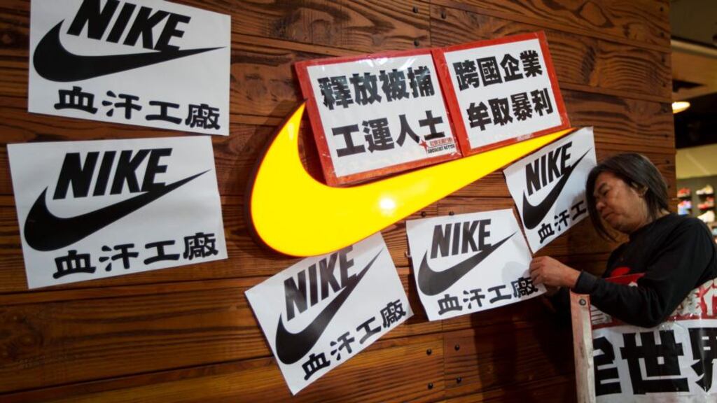 Pro-democracy lawmaker Leung Kwok-hung sticks a protest sign in support of a strike by workers of Yue Yuen Industrial Holdings in Dongguan, during International Labour Day in Hong Kong on May 1st, 2014.