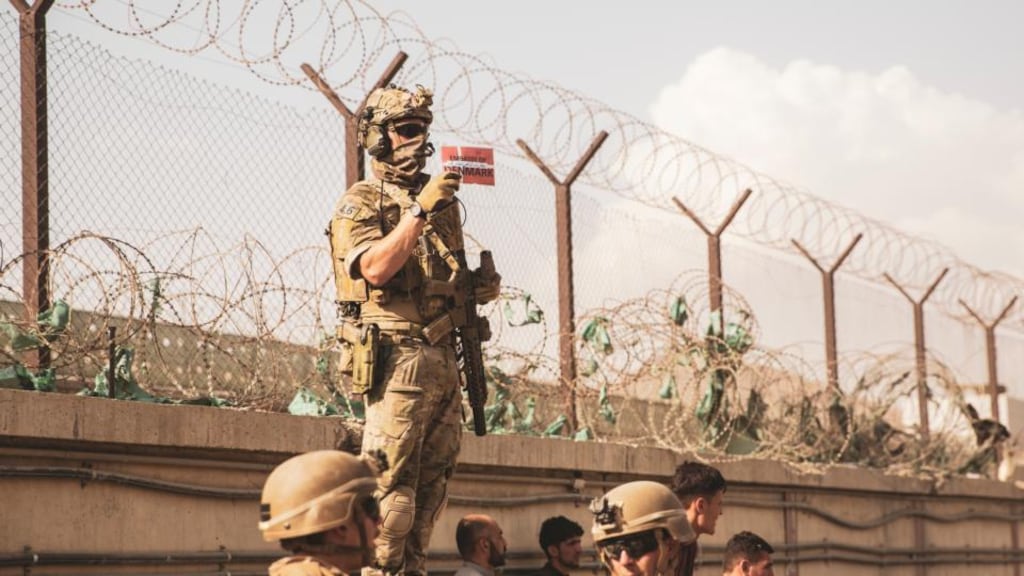A Danish coalition service member holds up a Danish flag to identify families during an evacuation at Hamid Karzai International Airport on Saturday. Photograph:y Staff Sgt. Victor Mancilla / US Marine Corps via Getty Images